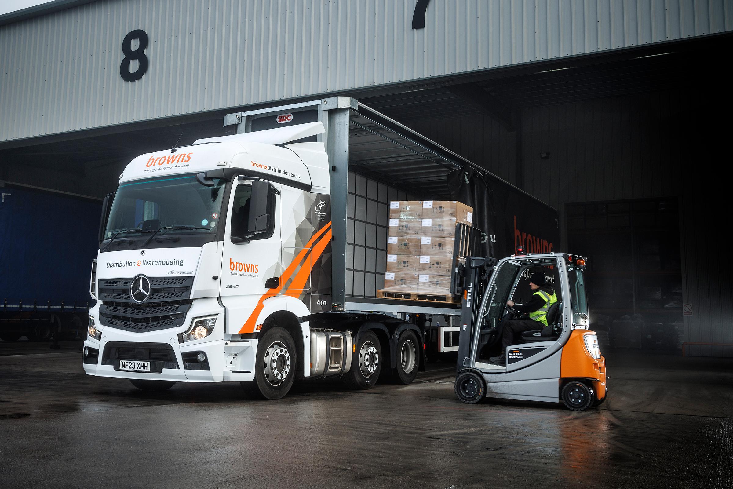 A forklift truck loads a pallet onto a trailer.